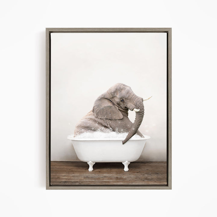 A gray elephant sitting in a white bathtub filled with bubbles, with its trunk raised in the air.