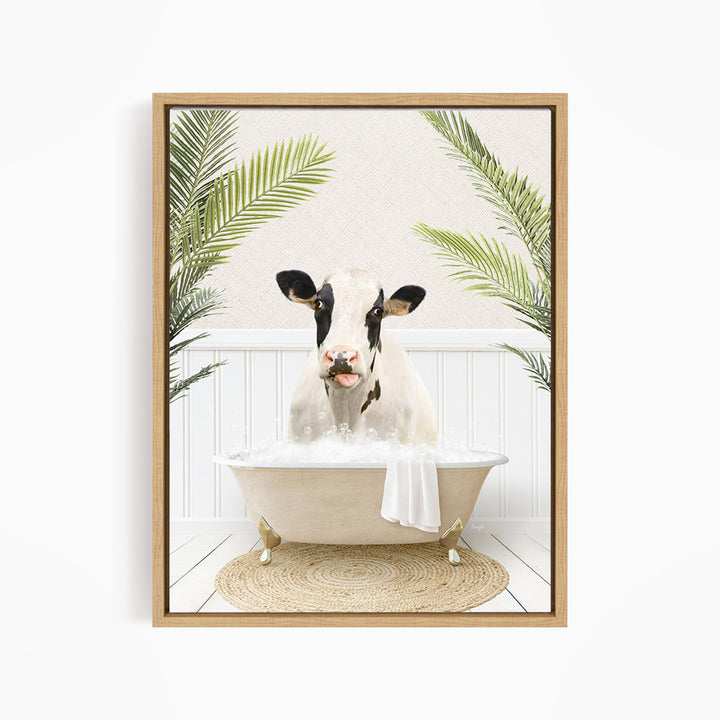A black and white cow is sitting in a white bathtub filled with water, surrounded by green palm leaves.