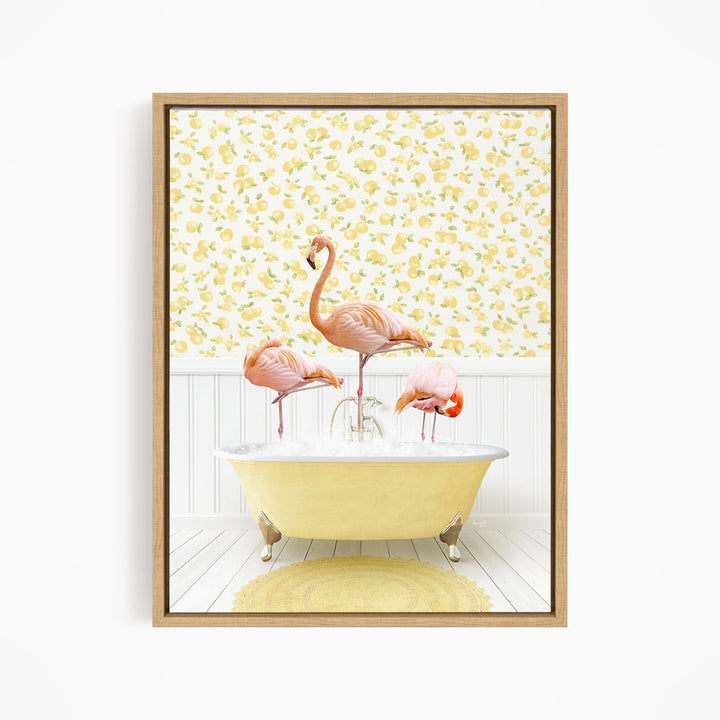 A framed image depicting three pink flamingos standing in a yellow bathtub, with a yellow and white floral wallpaper in the background.