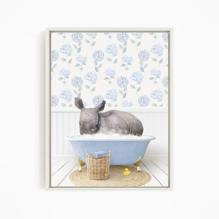 A rhinoceros is sitting in a blue bathtub filled with water, surrounded by a wicker basket and yellow rubber ducks.