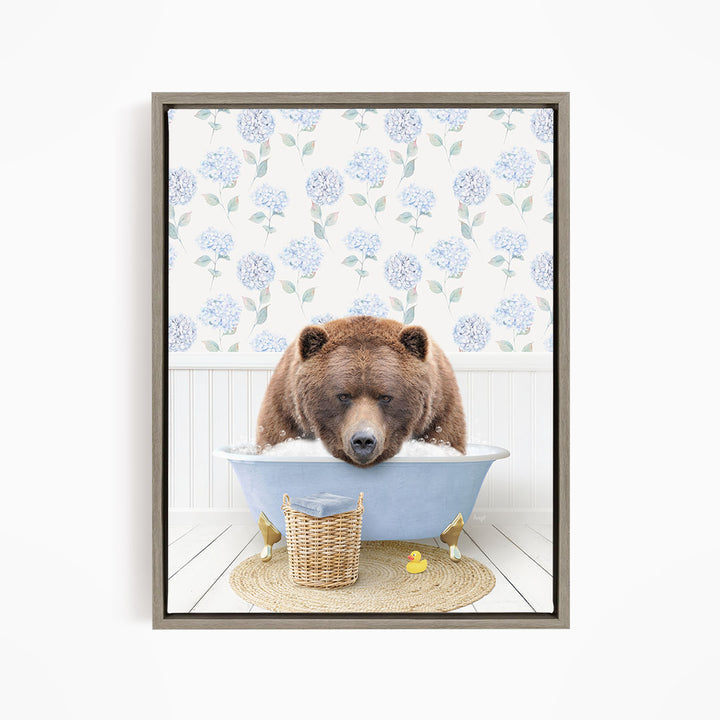 A brown bear is sitting in a blue bathtub filled with water, surrounded by a wicker basket and yellow rubber ducks.