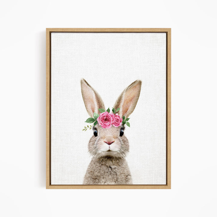 A cute rabbit wearing a pink flower crown on its head, looking directly at the camera.