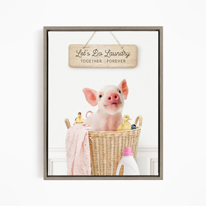 A cute pig sitting in a wicker basket filled with rubber ducks, accompanied by a wooden sign that reads "Let's Do Laundry Together Forever".