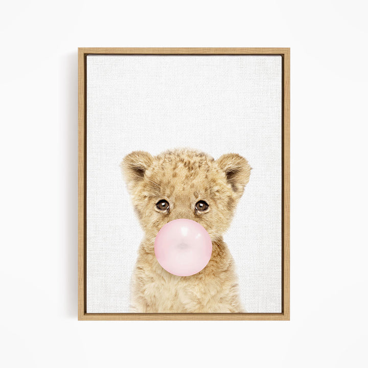 A cute baby lion blowing a bubble with a pink bubble gum bubble.