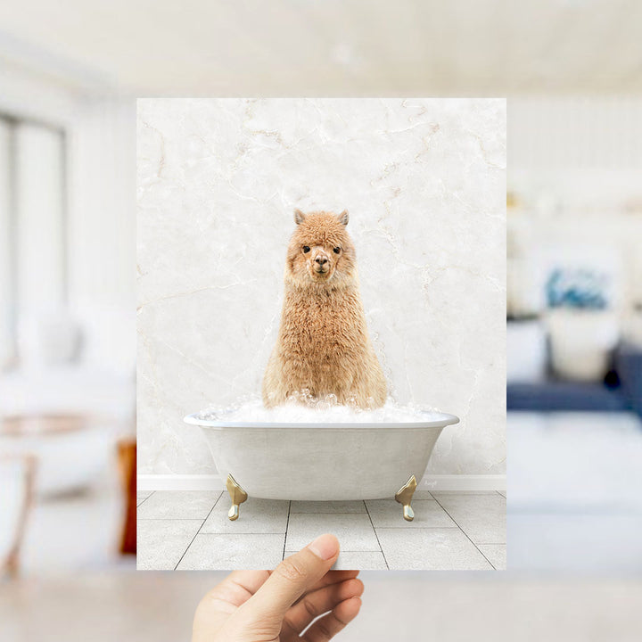 A fluffy brown alpaca sitting in a white bathtub filled with bubbles, with a blurred background suggesting a bathroom setting.