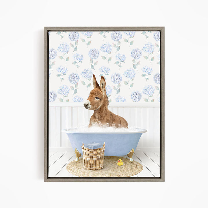 A donkey is sitting in a blue bathtub filled with water, surrounded by a wicker basket and rubber ducks.