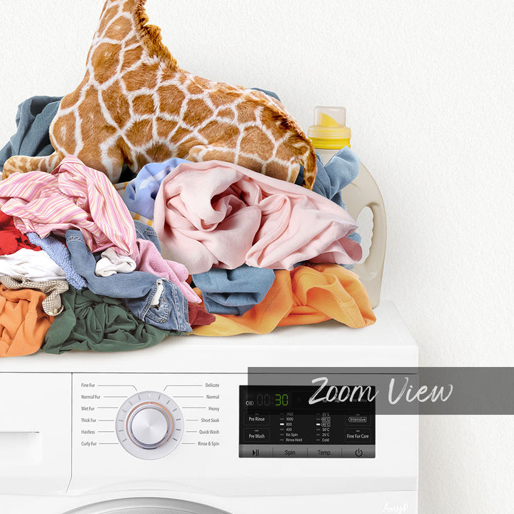A laundry basket filled with various clothes, including a stuffed giraffe, sits atop a washing machine with a digital display.