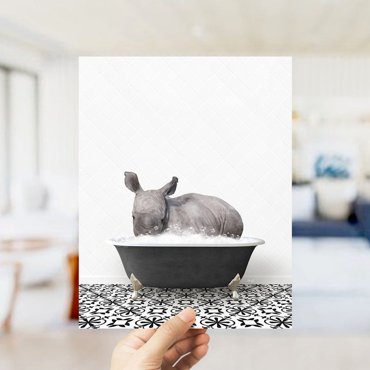 A rhinoceros is sitting in a bathtub filled with water, creating a whimsical and playful scene.