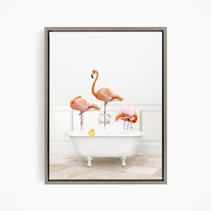 A framed image depicting three flamingos standing in a white bathtub filled with water, with a yellow rubber duck floating in the water.
