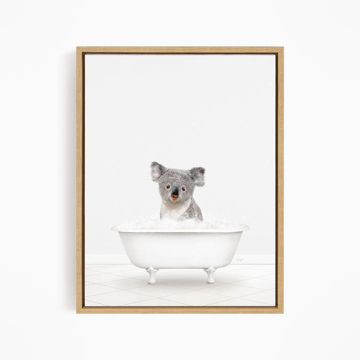 A koala sitting in a white bathtub filled with bubbles, looking directly at the camera.