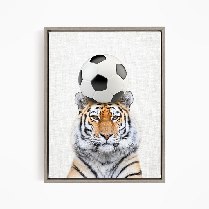 A tiger is sitting on a soccer ball, with the ball balanced on its head.