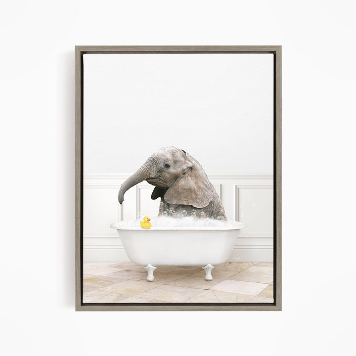 A gray elephant is sitting in a white bathtub, with a yellow rubber duck floating in the water.