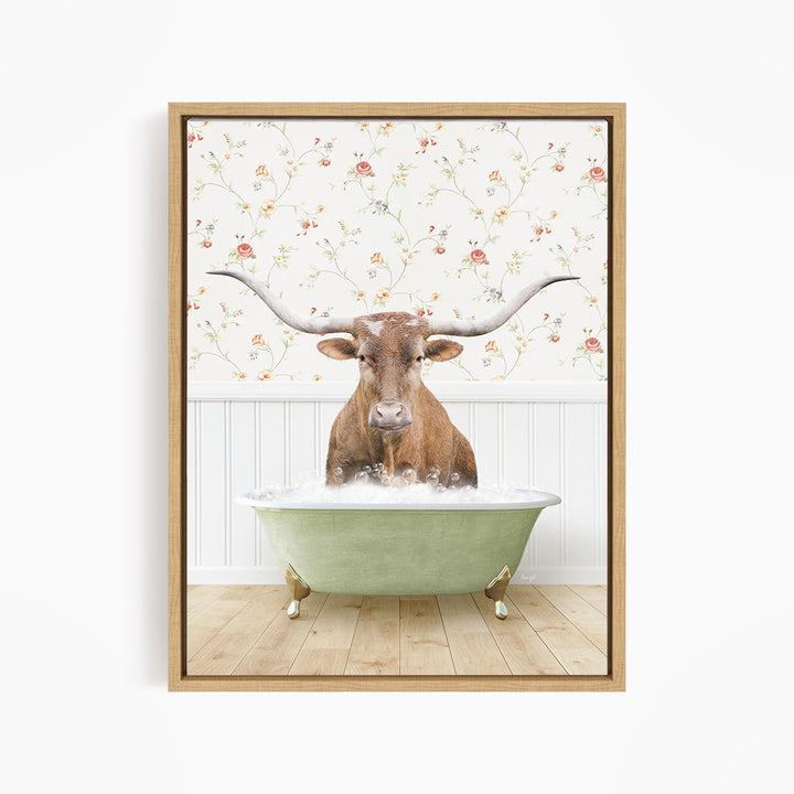 A brown cow with large horns is sitting in a green bathtub filled with water, surrounded by a floral wallpaper.