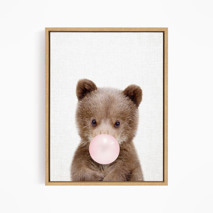 A cute brown bear is blowing a bubble with a pink bubble gum bubble.
