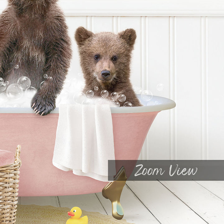 A baby bear sitting in a pink bathtub, surrounded by bubbles, with a yellow rubber duck nearby.