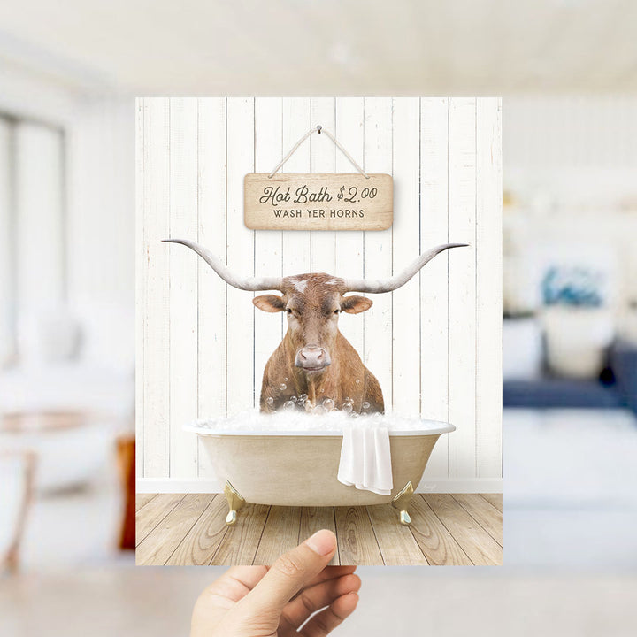 A hand holding a framed image of a bull with a sign above it that says "Hot Bath $2.00 WASH YER HORN".