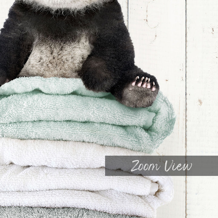A panda bear sitting on top of a stack of light blue towels.