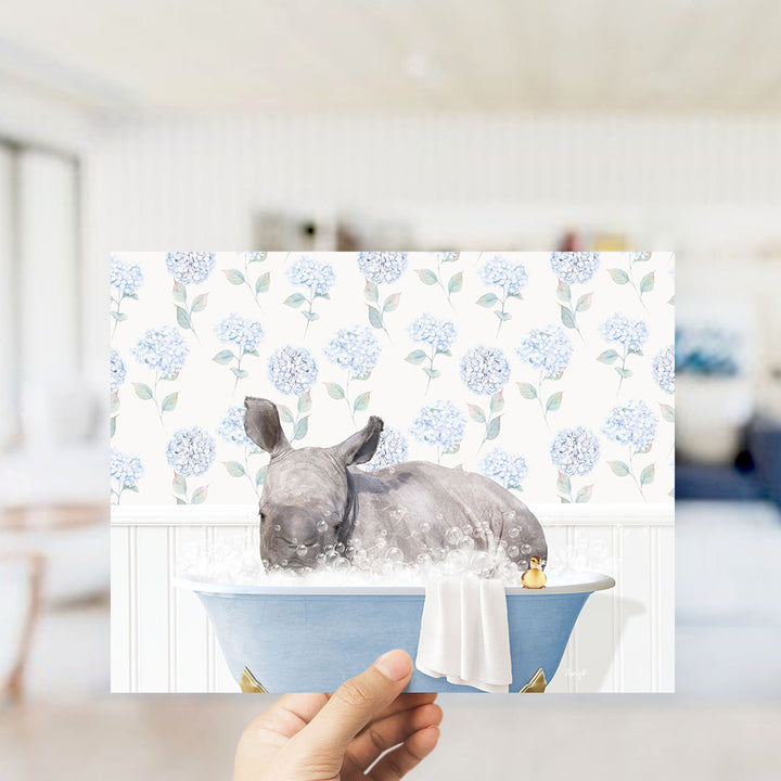 A rhinoceros is sitting in a blue bathtub filled with water, surrounded by blue flowers on the wall behind it.