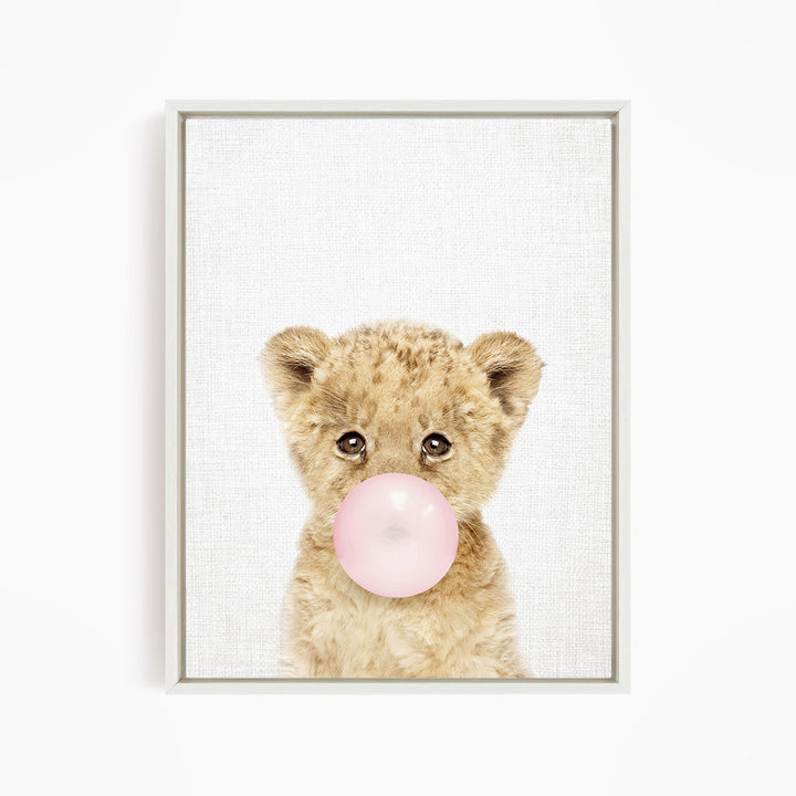 A cute baby lion blowing a bubble with a pink bubble gum bubble.