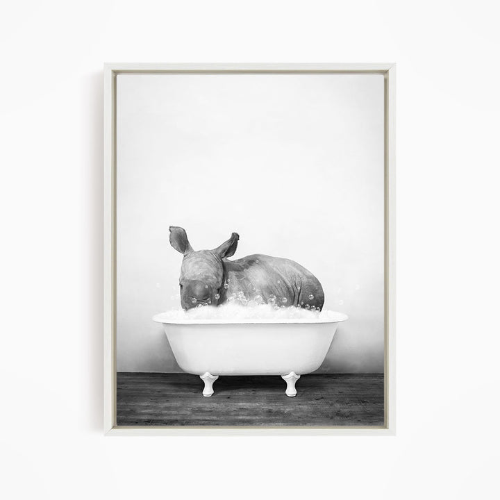 A rhinoceros is sitting in a white bathtub filled with water, creating a whimsical and playful scene.