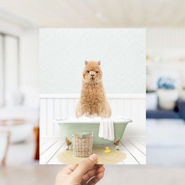 A fluffy brown alpaca sitting in a green bathtub filled with bubbles, surrounded by a yellow rubber duck and a white towel.