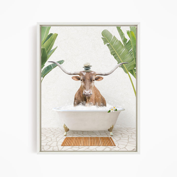 A bull with large horns is sitting in a white bathtub filled with water, surrounded by tropical plants and a wooden mat on the floor.