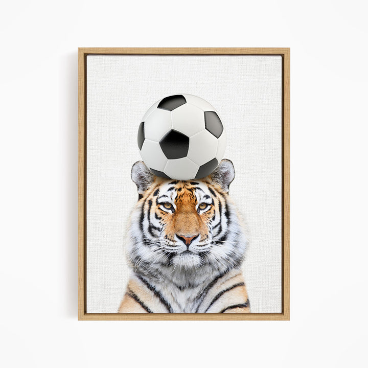 A tiger is balancing a soccer ball on its head, creating a playful and amusing scene.