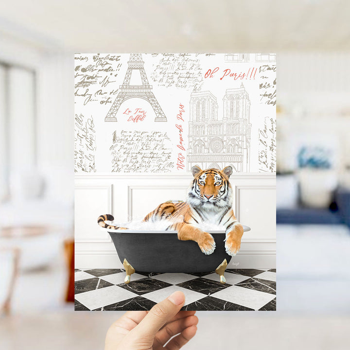A hand is holding up a printed image featuring a tiger sitting in a bathtub, with the Eiffel Tower and other Parisian landmarks visible in the background.
