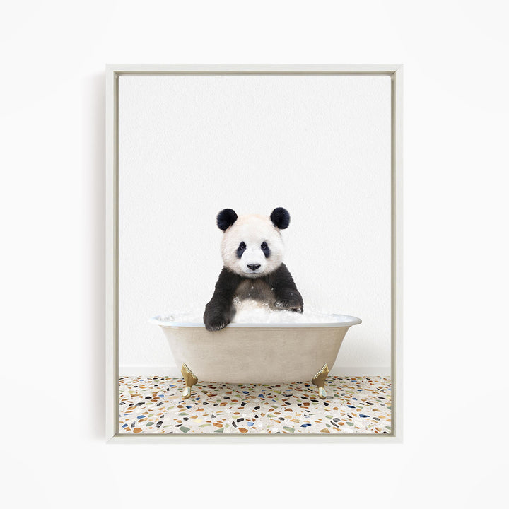 A panda bear sitting in a white bathtub filled with bubbles, looking directly at the camera.