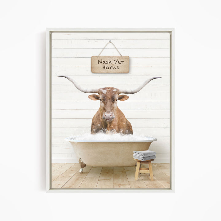 A brown steer with large horns is sitting in a bathtub filled with water, with a sign above it that says "Wash Yer Horns".