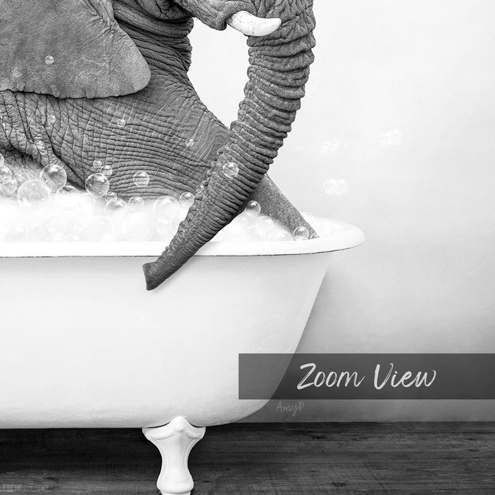 A close-up black and white image of an elephant sitting in a bathtub filled with bubbles.