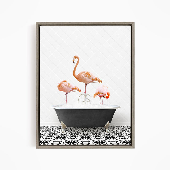 A framed image depicting three pink flamingos standing in a bathtub filled with water, with a black and white patterned tile floor beneath.