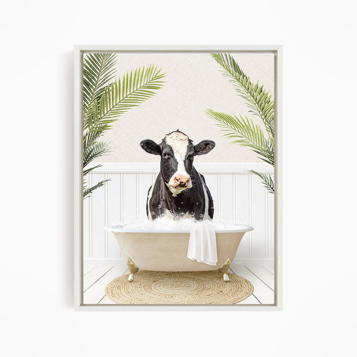A black and white cow is sitting in a white bathtub filled with water, surrounded by green palm leaves.