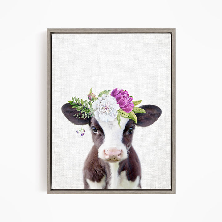 A framed print of a cow wearing a floral crown on its head.
