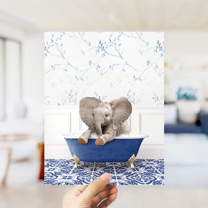 A small elephant sitting in a blue bathtub, surrounded by a blue and white floral patterned wall.