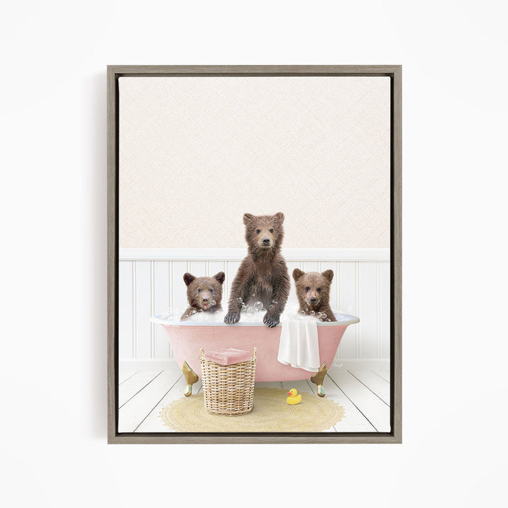 A framed image depicting three brown bears sitting in a pink bathtub, with a yellow rubber duck floating in the water.