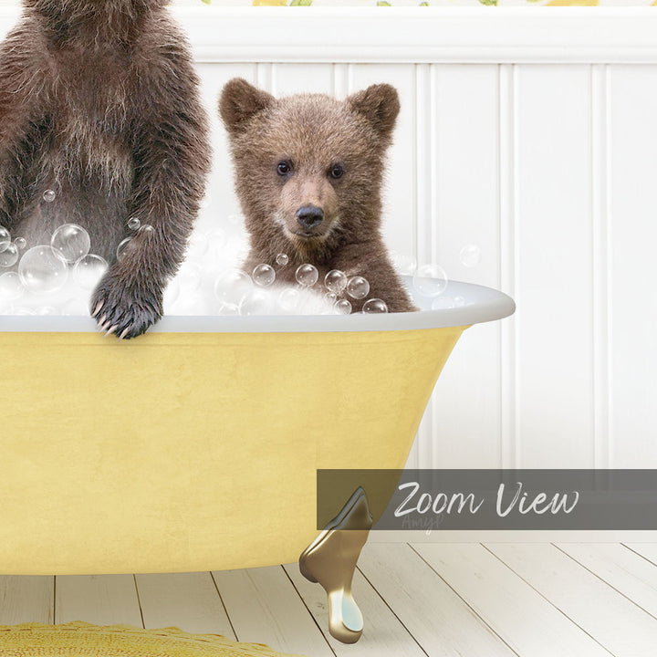 A young bear cub sitting in a yellow bathtub filled with bubbles, with a wooden floor and white walls in the background.