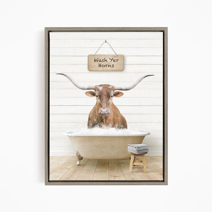 A framed image depicting a bull with large horns sitting in a bathtub, with a sign above that says "Wash Yer Horns".