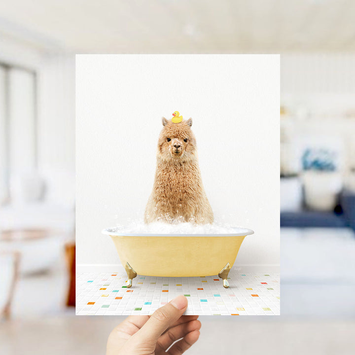 A brown alpaca sitting in a yellow bathtub filled with bubbles, with a yellow rubber duck on its head.