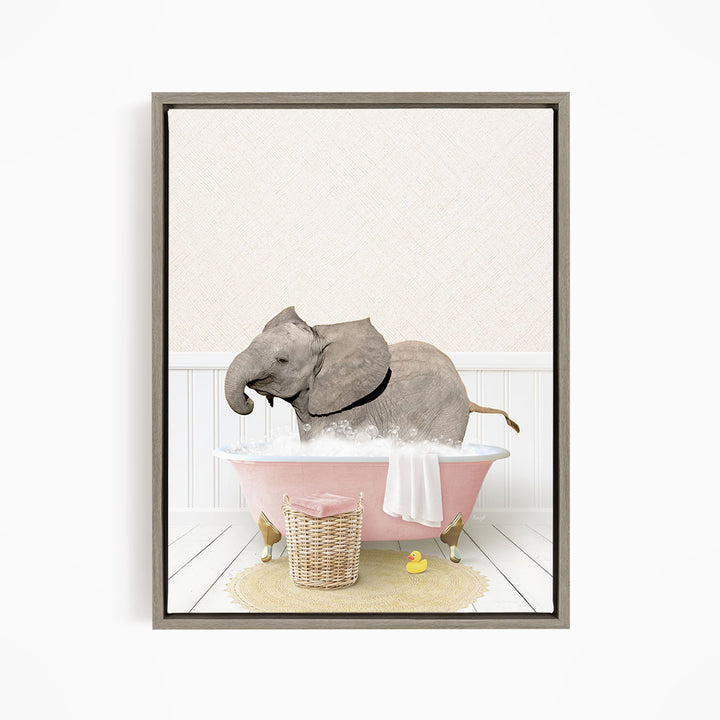 A gray elephant is sitting in a pink bathtub filled with water, surrounded by a yellow rubber duck and a basket.