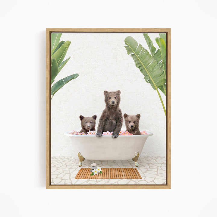 Three adorable brown bears sitting in a white bathtub filled with pink flowers, surrounded by green leaves.