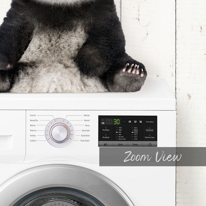 A panda bear sitting on top of a washing machine, with the control panel of the washing machine visible below.