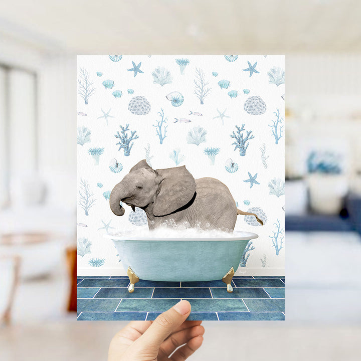 A hand is holding up a print featuring an elephant sitting in a bathtub filled with bubbles, surrounded by a blue and white ocean-themed background.