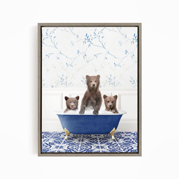 A framed image depicting three bears sitting in a blue bathtub, with a patterned tile floor and a floral wallpaper in the background.
