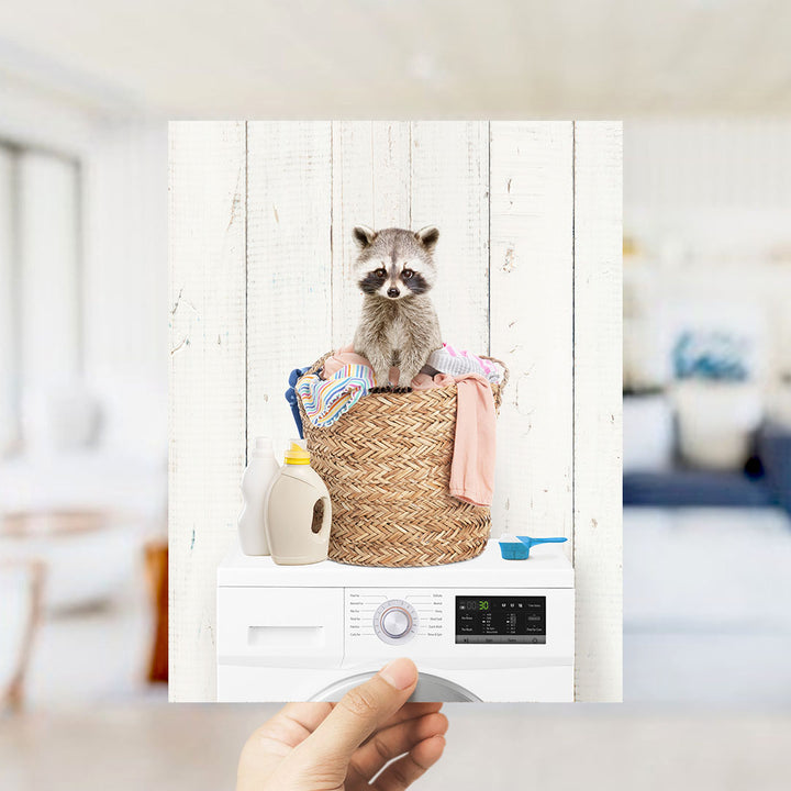A raccoon sitting in a basket filled with laundry, surrounded by various household items such as detergent and a bottle.