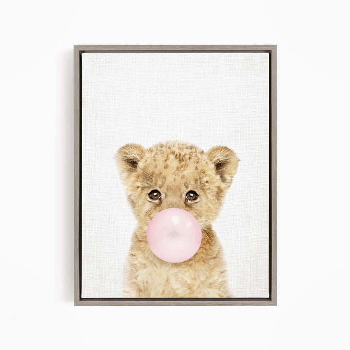 A cute baby lion blowing a bubble with a pink bubble gum bubble.