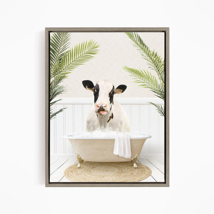 A black and white cow is sitting in a white bathtub filled with water, surrounded by green palm leaves.