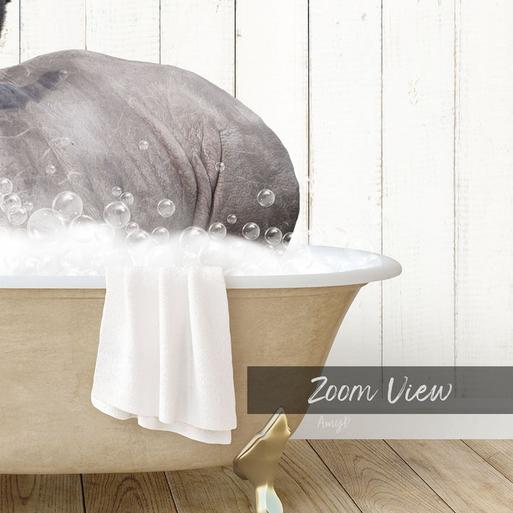 A bathtub filled with bubbles, with a towel hanging on the side and a wooden floor in the background.