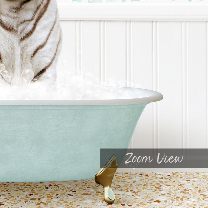 A white and black striped cat is standing in a light blue bathtub filled with bubbles, with a gold bathtub leg visible on the floor.