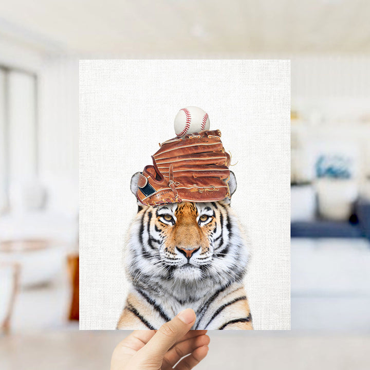 A tiger wearing a baseball cap and holding a baseball in its mouth.